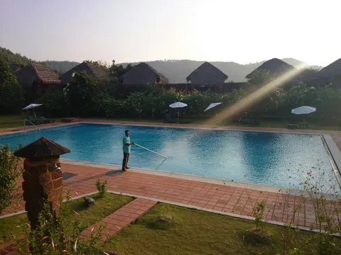 A pool technician skimming a pool in morning light
